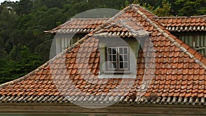 Roof of ancient house covered with old peeled red tile, cozy attic at home