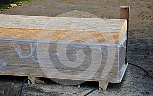 Roof battens beams and osb boards intended for construction lie unwrapped on the ground on a pallet. The slats are painted with th