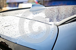 Roof of a blue car with a fin antenna of a radio receiver covered with raindrops after rain. closeup, soft focus. blur