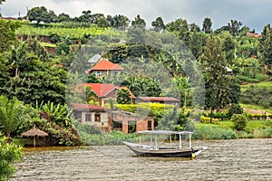Roof boat anchored at the coast with rwandan village in the background, Kivu lake, Rwanda
