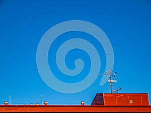 The roof of the building with ventilation and TV antennas, under the bright blue sky