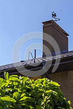 Roof and chimney with vane modern brick rustic cottage. Concept of investment in suburban real estate