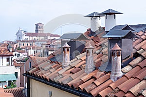 Roof with chimneys with blurred view over Venice in the early morning, Italy