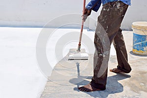 Roof coat white paint on a Concrete roof a Man painting on top of the Roof to Reduce heat on home