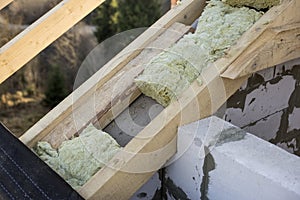 Roof construction and insulation with mineral wool. Wooden beams frame on walls of hollow foam insulation blocks. Roofing