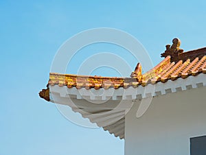 Roof corner of a traditional Chinese building with red tiles and clay figures