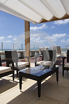 Roof in front of the sea with tanned beds, armchais, blue sky and white clouds