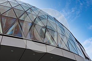 Roof and glass facade of modern skyscraper, blue sky