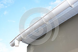 Roof gutter repair. Rain gutter installation with drain downspout pipe. Guttering with soffits photo