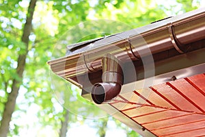 Roof of house with plastic rain gutter on beautiful natural background with green vegetation