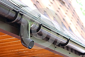 Roof of house with plastic rain gutter on beautiful natural background with green vegetation