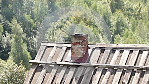 Roof of a house with a smokehouse and smoke from a smokehouse in the mountains in the carpathians in ukraine, stoking the stove