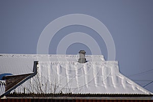 The roof of house is in the snow. House with chimney.