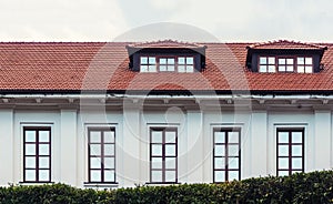 The roof of the house is tiled. Window on the roof of the house. Attic. Blue cloudy sky