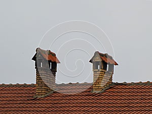 The roof of the house with tiles and two chimneys of the house made of bricks