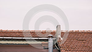 Roof of a house with two chimneys and roof made of red color bricks