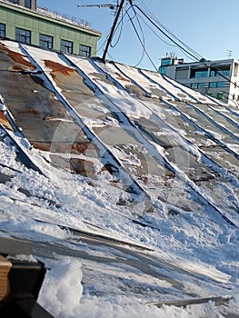 The roof is iron, rusty, old, powdered with snow on a winter day