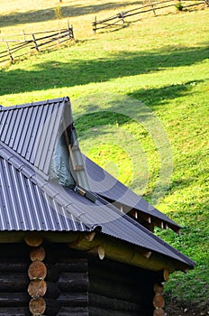 The roof is made of gray embossed metal sheets. Wooden house in the summer fiel