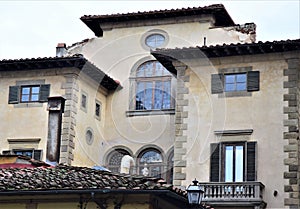 A roof made of tiles and the beautiful historic facade, with large windows, of a building located not far from the Piazza della Sa