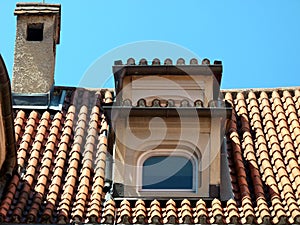 Roof of a medieval house with dormer roof tiles and fireplace with brick cover