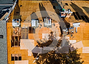 Roof repairs of an apartment building in worker with replacing gray asphalt shingles on house roofing construction worker standing