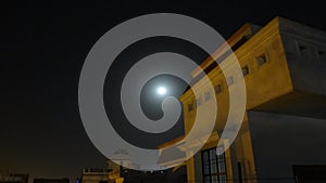 Roof top Lit by yellow street light on a full moon night