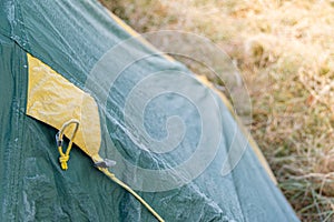 Roof of tourist tent under the morning sun. Green waterproof fabric was covered with cold and condensation from frost