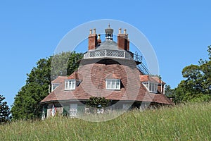 The roof of an unusual historic sixteen sided house on a beautiful sunny summers day in Devon, England seen from across the meadow