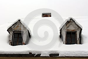 Roof windows on old abandoned house covered with deep snow