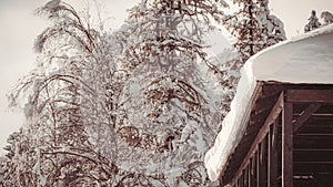 Roof of wooden house is covered with snow. Sudden snowfall poured frost and ice