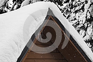 Roof of wooden house is covered with snow. Sudden snowfall poured frost and ice