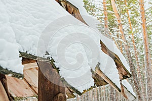 Roof of wooden house is covered with snow. Sudden snowfall poured frost and ice