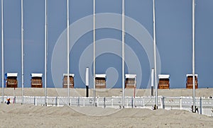 Roofed wicker beach chairs and flagpoles