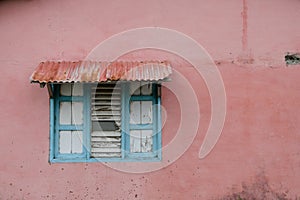 Roofed window with closed wooden shutter - colorful building ext