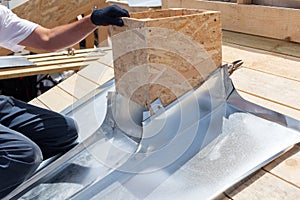 Roofer builder worker attach metal sheet to the chimney.