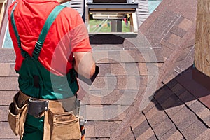 Roofer builder worker with bag of tools installing roofing shingles.