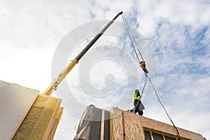 Roofer builder worker with crane installing structural Insulated Panels SIP. Building new frame energy-efficient house.