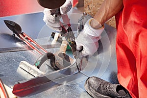 Roofer builder worker finishing folding a metal sheet using metal shears.