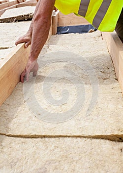 Roofer builder worker installing roof insulation material on new house under construction.