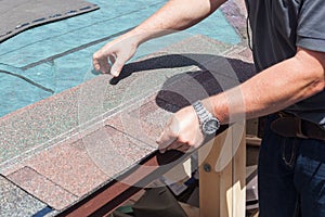 Roofer builder worker installing roof shingles.