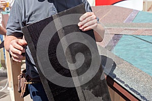 Roofer builder worker installing roof shingles.