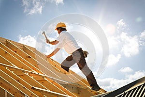 Roofer carpenter working on roof on construction site