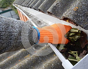 Roofer Cleaning Rain Gutter from Leaves. Roof Gutter Cleaning. House Gutter Cleaning