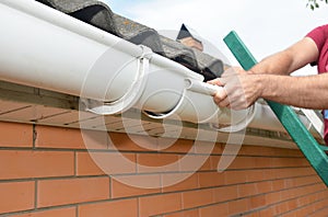 Roofer contractor installing and repair roof gutter. Guttering repair with hands.