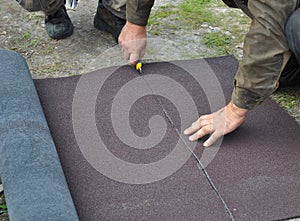 Roofer cutting roll roofing felt or bitumen during waterproofing works