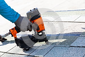 Roofer installing roof shingles with nail gun