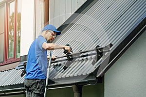 Roofer installing snow guard on metal roof