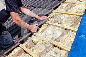 A roofer laying tile on the roof