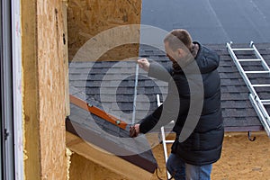 Roofer measuring tiles on a new house