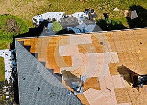 A roofer nailing shingles with air gun, replacing roof cover protection being applied
